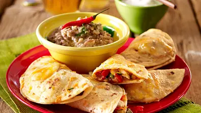 Gefüllte Käse-Tortillas mit Bohnenpüree auf einem rotem Teller serviert. - Foto: LECKER @ Bauer Media Group