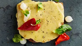 Raclette-Brot mit zerlaufenem Raclette-Käse, garniert mit Silberzwiebeln und eingelegter Paprika. - Foto: LECKER @ Bauer Media Group