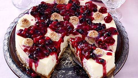 Raffaelo-Beeren-Käsekuchen auf Servierplatte, ein angeschnittenes Stück auf Tortenheber - Foto: House of Food / Bauer Food Experts KG
