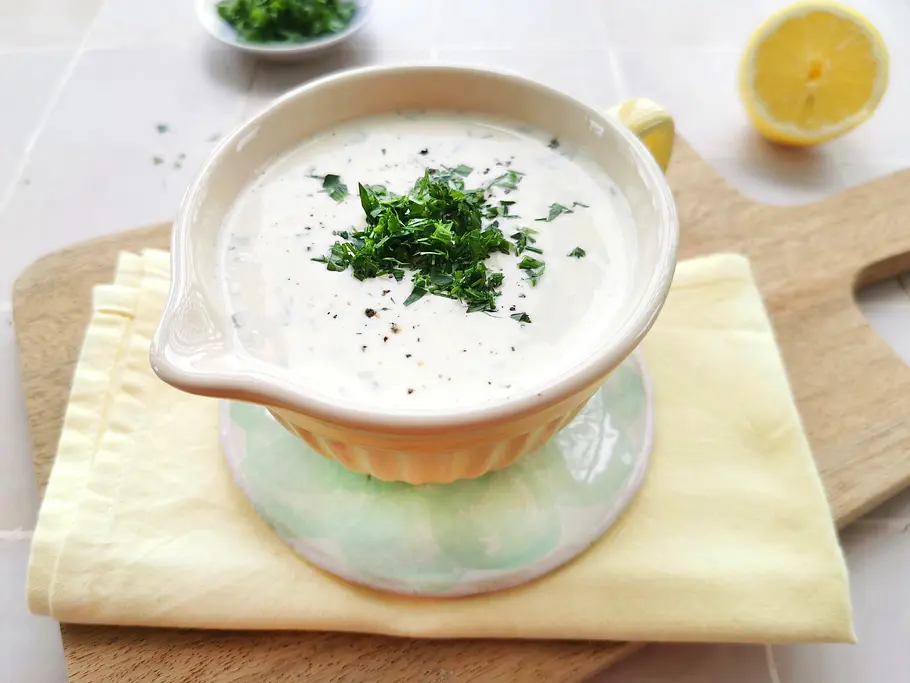 Dip Ranch-Dressing mit Kräutern in einer gelben Keramik-Schale mit Gießer und Henkel