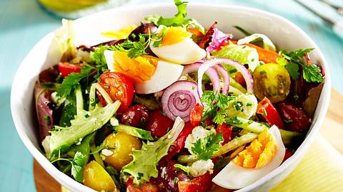 Schneller Salat mit Ei und Feta in einer weißen Schüssel, im Hintergrund steht ein Olivenöl-Fläschchen - Foto: House of Food / Bauer Food Experts KG