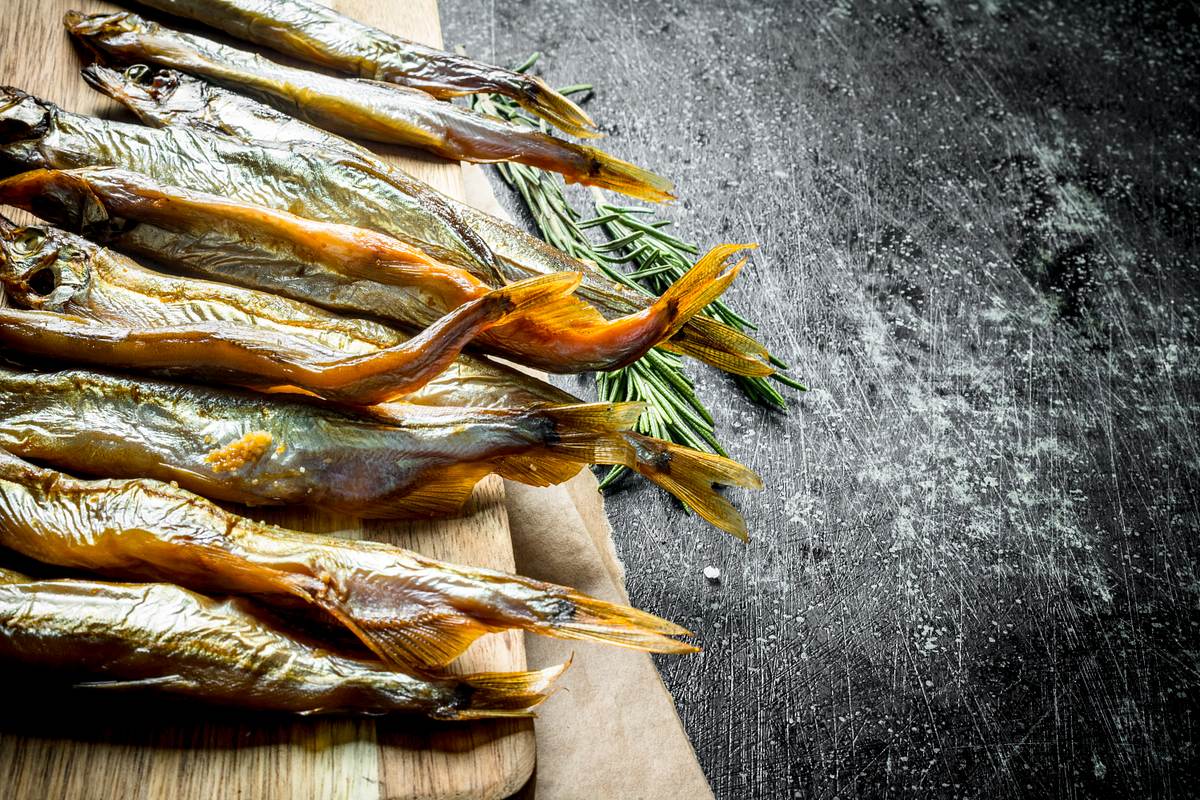 Geräucherter Fisch auf einem Holzbrett im rustikalen Hintergrund