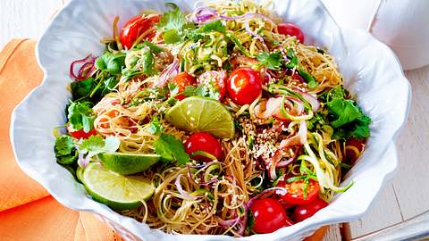 Reisnudeln mit buntem Sommergemüse, Limettenspalten und frischem Koriander in einer großen Servierschüssel - Foto: House of Food / Bauer Food Experts KG