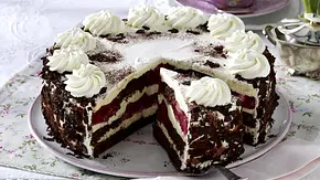 Mehrschichtige Rhabarbertorte mit dunklen Biskuitböden, Sahneschichten und Rhabarberfüllung, verziert mit Sahnetuffs und Schokoraspeln, angerichtet auf einer floralen Tortenplatte. - Foto: LECKER @ Bauer Media Group Mehrschichtige Rhabarbertorte mit dunklen Biskuitböden, Sahneschichten und Rhabarberfüllung, verziert mit Sahnetuffs und Schokoraspeln, angerichtet auf einer floralen Tortenplatte. - Foto: LECKER @ Bauer Media Group