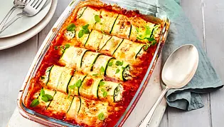 Zucchini-Röllchen mit cremiger Füllung in Tomatensauce, überbacken mit Käse, serviert in einer Auflaufform und garniert mit frischen Kräutern. - Foto: LECKER @ Bauer Media Group