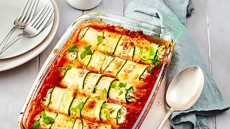 Zucchini-Röllchen mit cremiger Füllung in Tomatensauce, überbacken mit Käse, serviert in einer Auflaufform und garniert mit frischen Kräutern. - Foto: House of Food / Bauer Food Experts KG