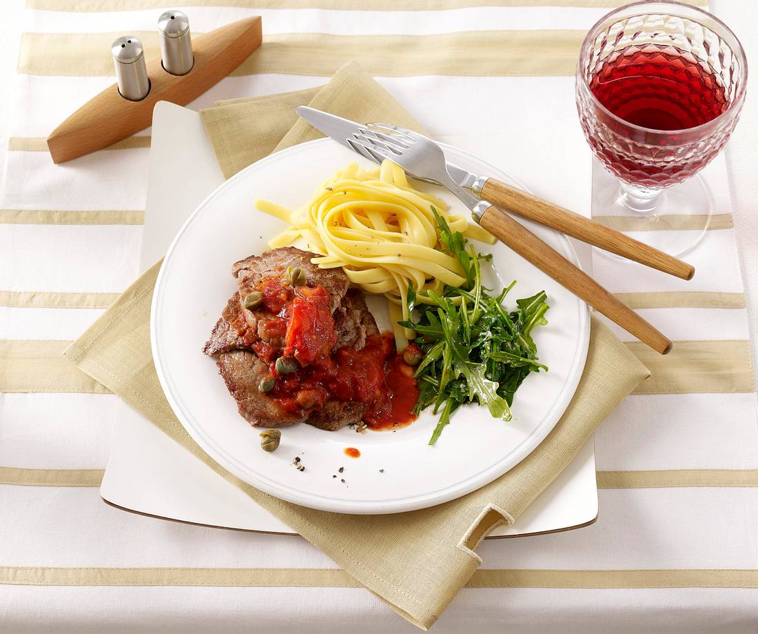 Rinderfiletschnitzel in pikanter Tomatensoße mit Rauke und Bandnudeln ...