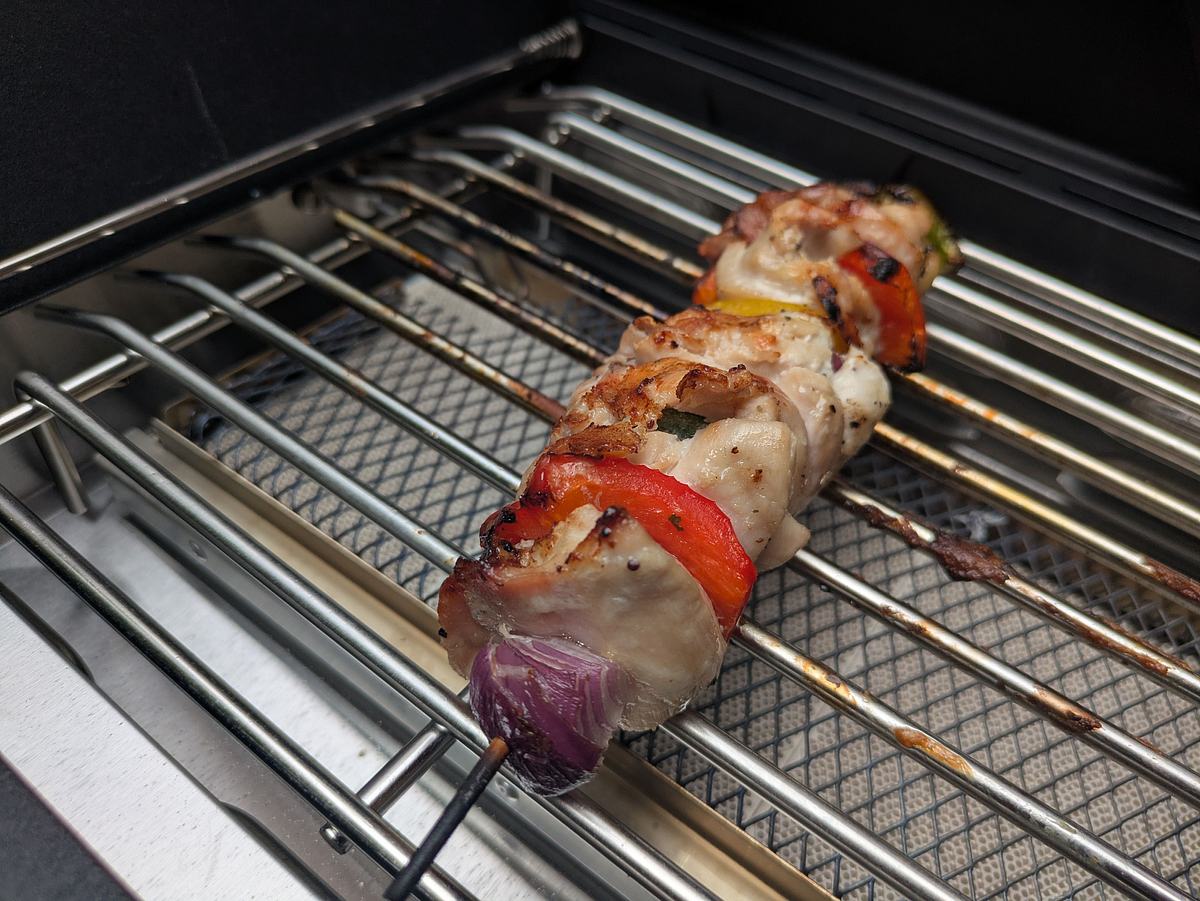 Ein Grillspieß mit Fleisch und Gemüse liegt auf der Primezone des Rösle Allflame Hero 4 Gasgrills.