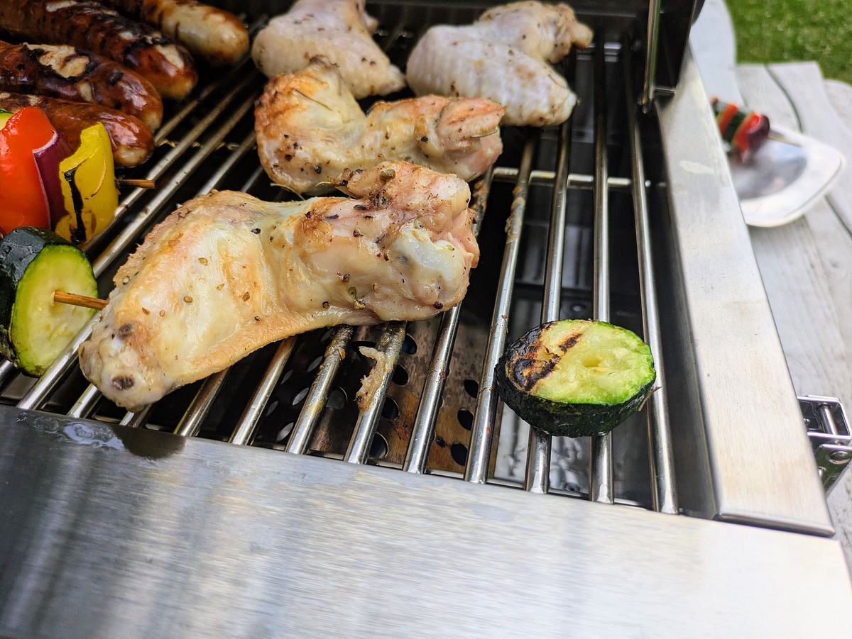 Rösle Videro G2-P Chicken Wings Hähnchenschenkel und gegrillte Zucchini liegen auf dem Grillrost des Videro G2-P.