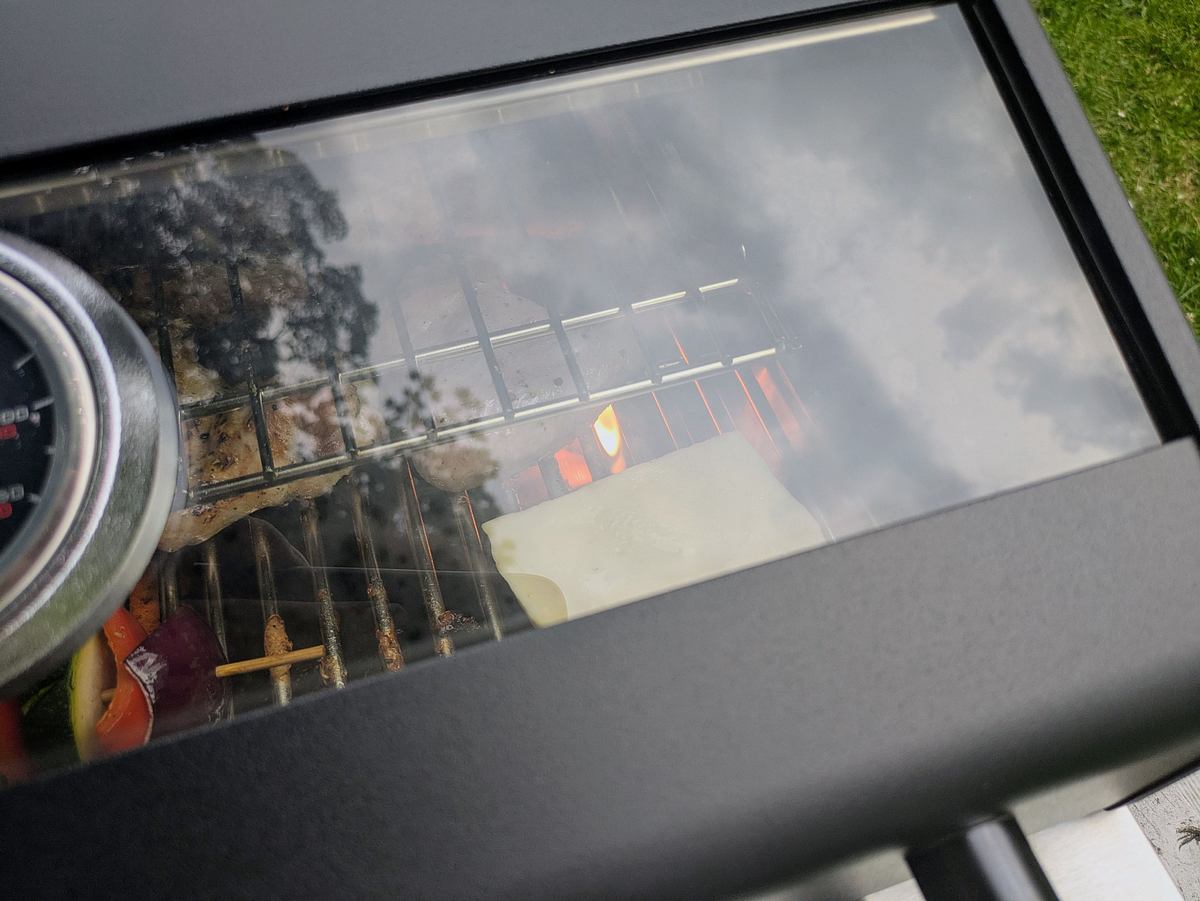 Rösle Videro G2-P Sichtfenster Sichtfenster im Deckel des Videro G2-P zeigt Grillgut wie Spieße und Käse auf dem Rost im Testbetrieb.