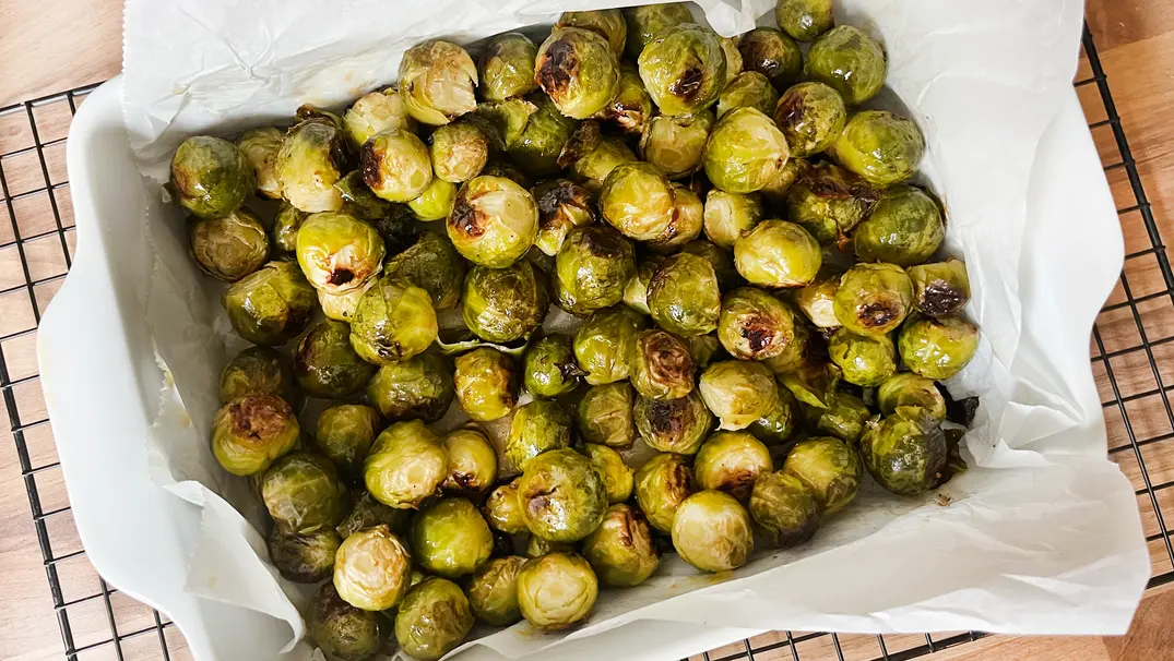 Gerösteter Rosenkohl aus dem Ofen in einer weißen Auflaufform mit weißem Backpapier - Foto: LECKER @ Bauer Media Group / Anne Kurz