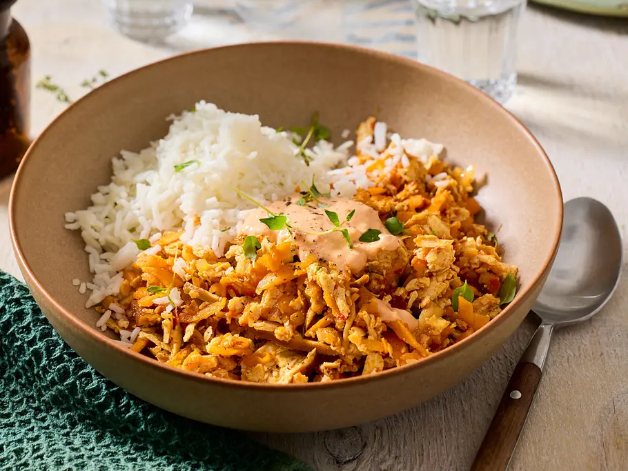 Impro-Curry Rezept Schüssel mit weißem Reis und einer Mischung aus gebratenen Möhren, Räuchertofu und frischen Kräutern, garniert mit einer cremigen Sauce.