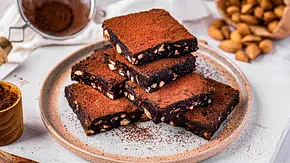 Sechs übereinander gestapelte, quadratische Stücke Brownies mit Kakao bestäubt - Foto: ShowHeroes für LECKER @ Bauer Media Group