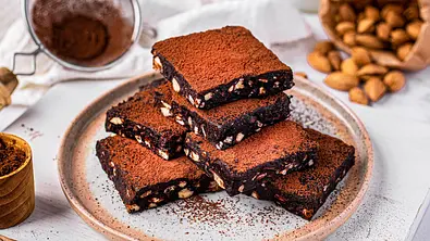 Sechs übereinander gestapelte, quadratische Stücke Brownies mit Kakao bestäubt - Foto: ShowHeroes für LECKER @ Bauer Media Group
