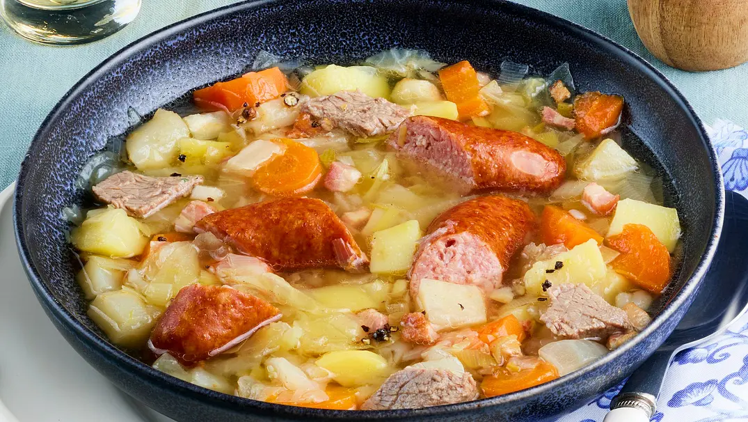 Eine Schale ist gefüllt mit würzigem Eintopf aus Steckrübe, Möhren, Suppenfleisch und geschnittener Schmorrwurst. - Foto: LECKER @ Bauer Media Group