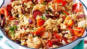 Schnelle Paella mit gebratenem Hähnchen, Chorizo und Paprika serviert in einer weißen Auflaufform und mit frischen Kräutern garniert - Foto: House of Food / Bauer Food Experts KG