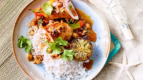 Auf einer Strandmatte liegt ein Teller mit Schnitzelröllchen und Basmatireis mit frischem Koriander und Zitronenscheibe - Foto: House of Food / Bauer Food Experts KG