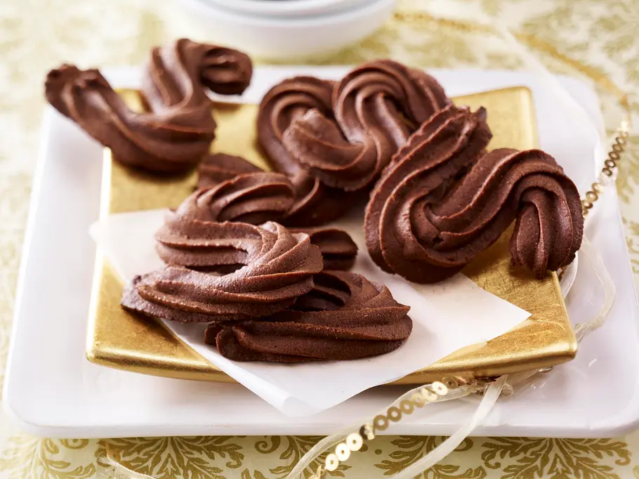 Schoko-Spritzgebäck in S-Form liegt auf einem goldenen Teller