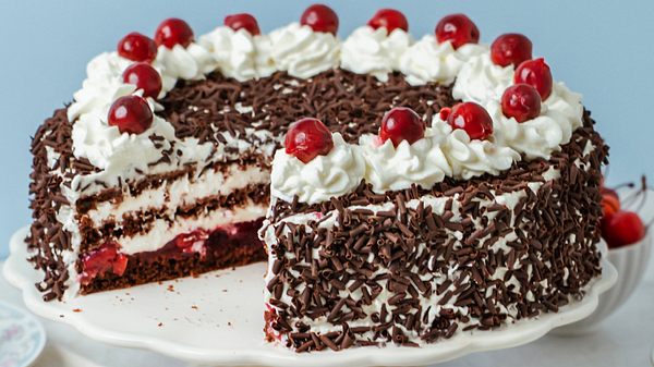 Die klassische Schwarzwälder Kirschtorte ist angeschnitten, sodass die Schichten aus Schokobiskuit, Sahne und Kirschen zu erkennen sind. - Foto: LECKER @ Bauer Media Group / StockFoodStudios