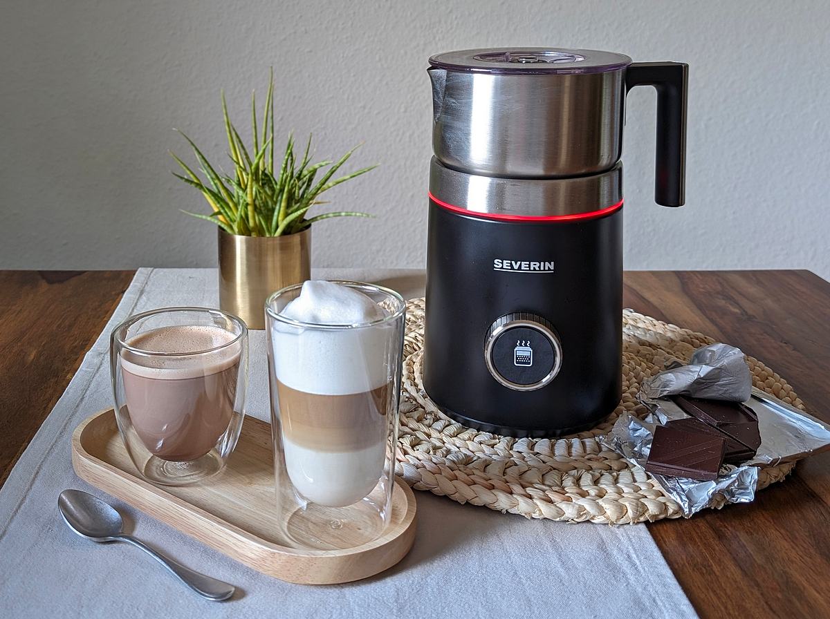 Der Severin Spuma 700 Plus SM 3587 neben einem Latte Macchiato und einem Glas heiße Schokolade.