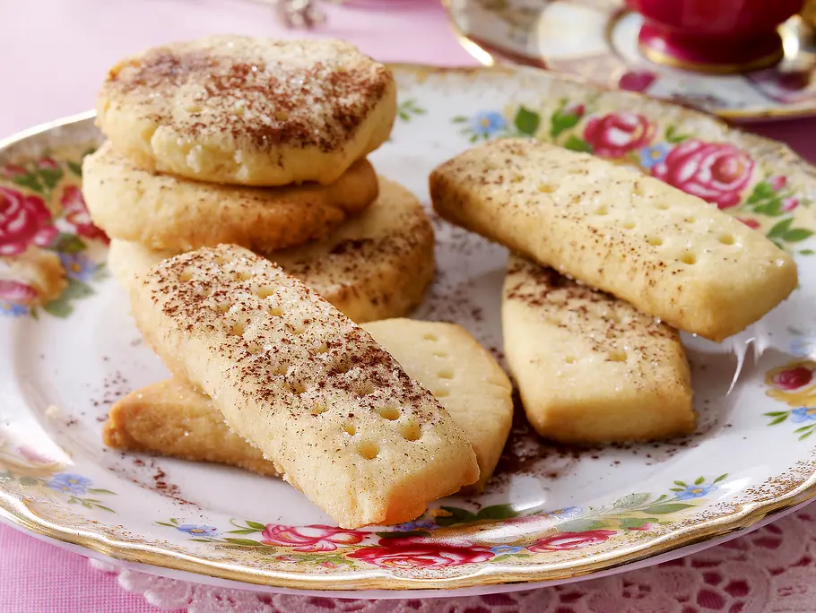 Shortbread Rezept Mit Kakao bestäubtes Shortbread in länglicher und runder Form liegt auf einem geblümten Kuchenteller
