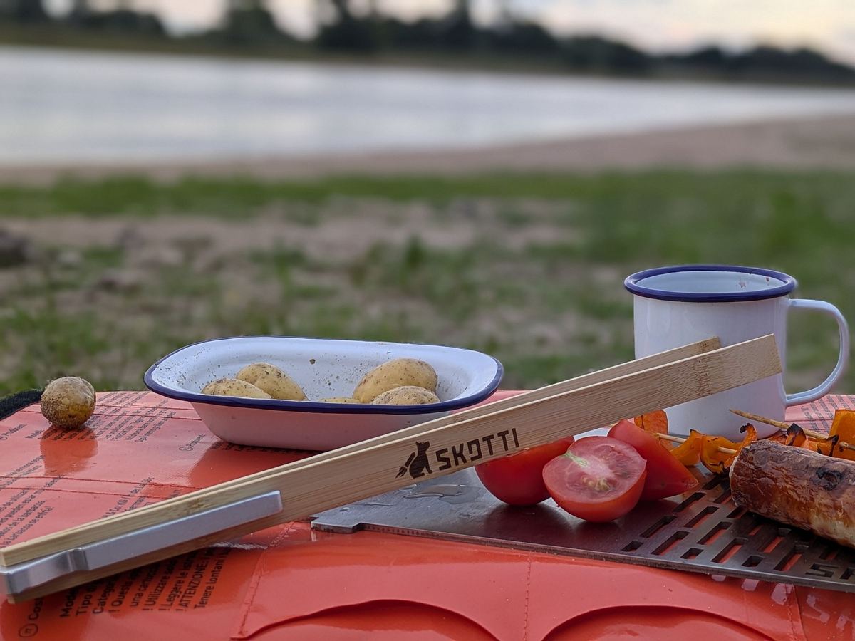 SKOTTI Tongs neben Camping-Geschirr am Fluss.