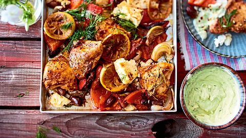 Hähnchenschenkel auf einem Blech mit Zitronenscheiben, Tomate und Oliven - Foto: House of Food / Bauer Food Experts KG