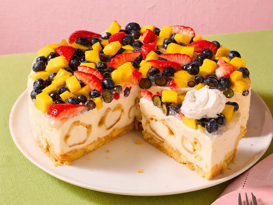 Sommerliche Windbeutel-Torte ohne Backen Luftige Windbeutel-Torte mit heller Cremefüllung, belegt mit bunten frischen Früchten wie Mango, Blaubeeren und Erdbeeren und im inneren der Cremefüllung sind Mini-Winbeutel.