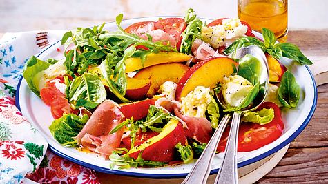 Sommerlicher Nektarinen-Mozzarella-Salat mit Schinken und Rucola auf einem Teller mit Besteck - Foto: House of Food / Bauer Food Experts KG