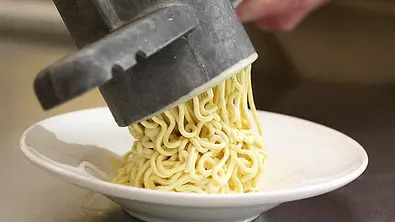 Vanilleeis wird aus einer eisgekühlten Spaghettieispresse auf einen tiefen Dessertteller gespritzt. - Foto: LECKER @ Bauer Media Group