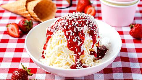 Spaghetti-Eis in einer kleinen Schale auf einem Tisch mit Erdbeeren und Waffeln - Foto: ShowHeroes