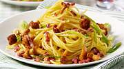 Ein weißer Teller mit Spaghetti, Pfifferlingen, Speckstücken und Lauchzwiebelringen. - Foto: House of Food / Bauer Food Experts KG