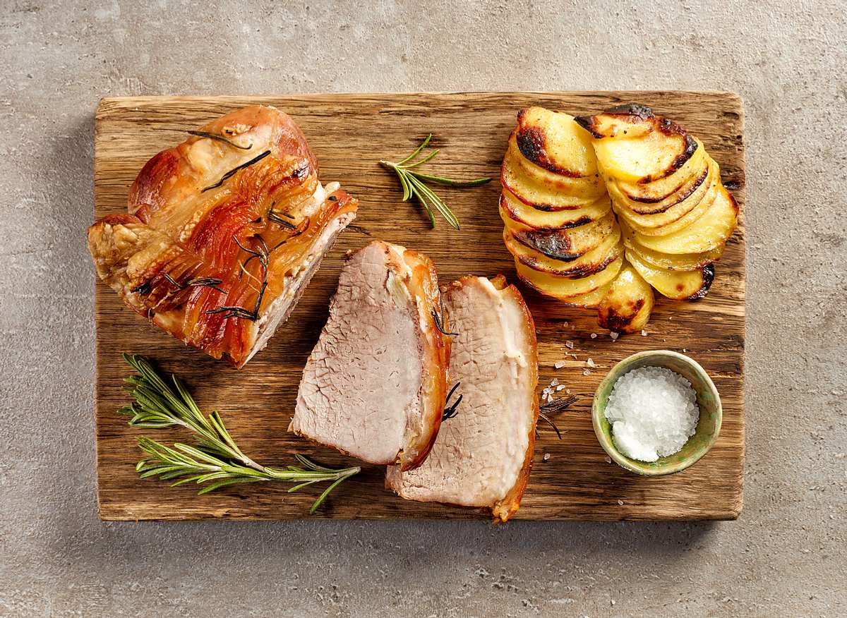 Schweinefleisch mit Kartoffeln auf einem rustikalem Holzbrett