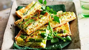 Quiche-Stücke mit grünem Spargel und frischen Kräutern liegen auf einem Tablett und sind bereit zum Mitnehmen. - Foto: LECKER @ Bauer Media Group Quiche-Stücke mit grünem Spargel und frischen Kräutern liegen auf einem Tablett und sind bereit zum Mitnehmen. - Foto: LECKER @ Bauer Media Group