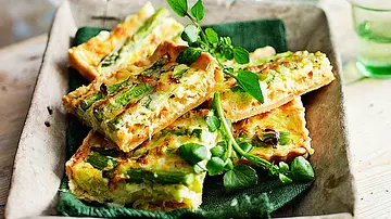 Quiche-Stücke mit grünem Spargel und frischen Kräutern liegen auf einem Tablett und sind bereit zum Mitnehmen. - Foto: LECKER @ Bauer Media Group