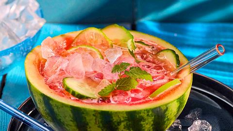 Wassermelonen-Limonade in einer ausgehöhlten Wassermelonen-Hälfte mit vielen Eiswürfeln und Gurkenscheiben-Deko. - Foto: House of Food / Bauer Food Experts KG