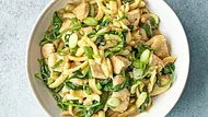 Spätzle mit zarten Hähnchenstücken, grünem Curry und frischem Blattspinat, garniert mit Frühlingszwiebeln, serviert auf einem weißen Teller. - Foto: Simone Neufing/MOE‘S QUICK & EASY FOOD