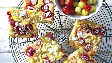 Fünf saftige Blechkuchenstücke mit frischen roten und grünen Stachelbeeren, großzügig mit Puderzucker bestäubt  auf einem  runden Kuchengitter. - Foto: LECKER @ Bauer Media Group