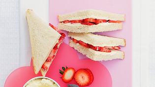 auf einer pinken Blumenplatte sind drei Sandwiches mit Erdbeeren und Frischkäse angerichtet - Foto: StockFood / Great Stock!