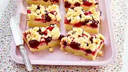 Sechs Stücke Streusel-Pudding-Schnitten mit Beeren auf einem rosa Tablett, am Rand ein Kuchenmesser - Foto: LECKER @ Bauer Media Group