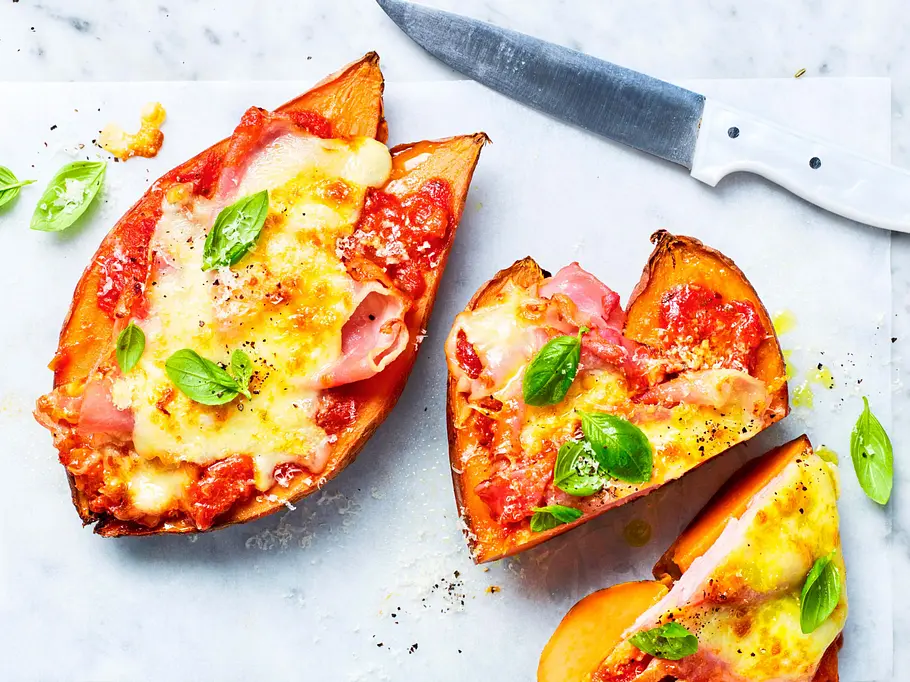 Die Süßkartoffeln sind für die Pizza halbiert, mit Tomatensoße bestrichen und Käse überbacken.