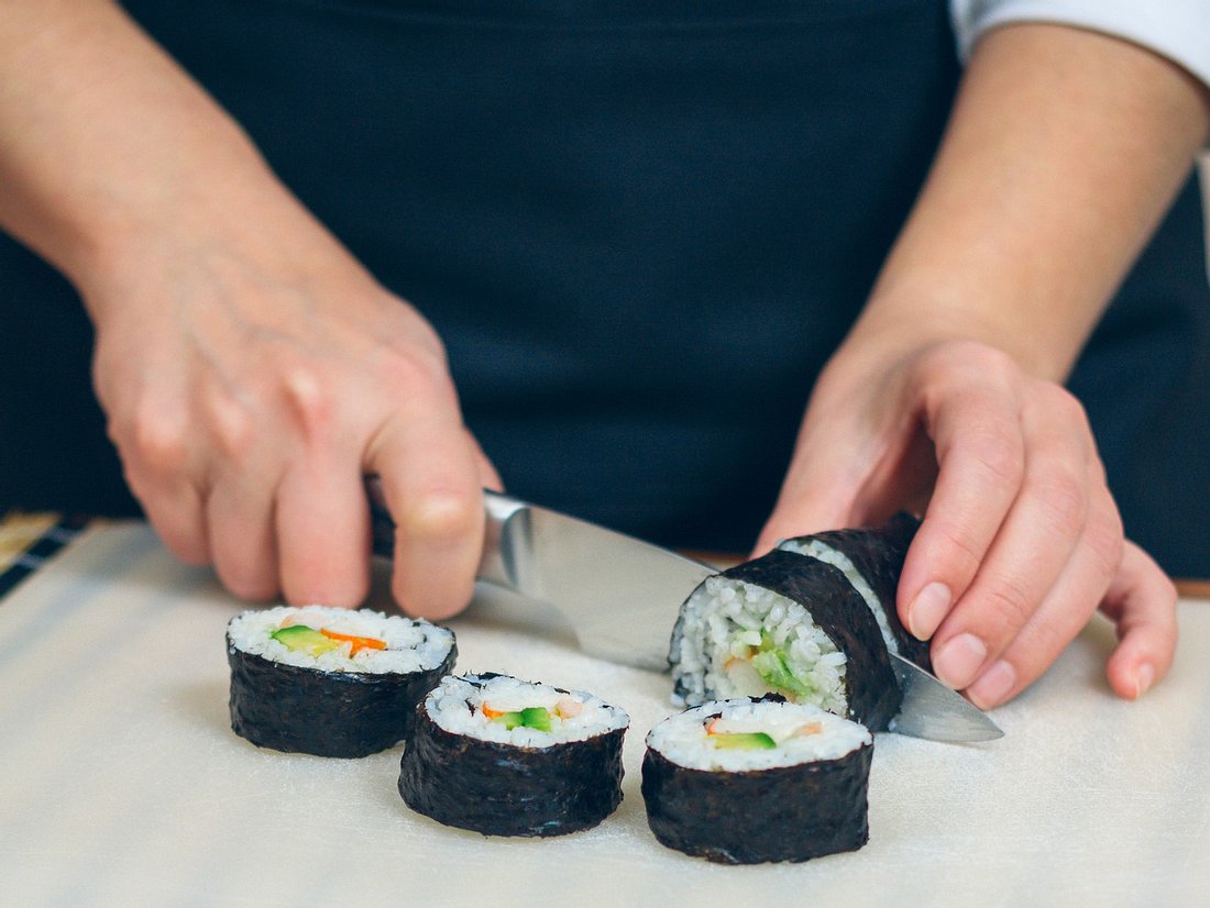 Person schneidet Sushi mit Sushimesser