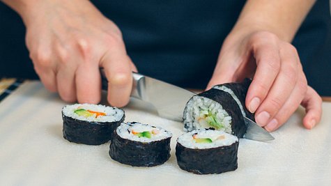 Person schneidet Sushi mit Sushimesser - Foto: iStock/doble-d