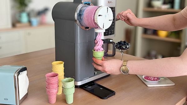 Ein Waffelhörnchen gehalten von einer Hand, in das die Ninja Swirl Softeis hineinfüllt. - Foto: Franziska Hoppe / LECKER.de
