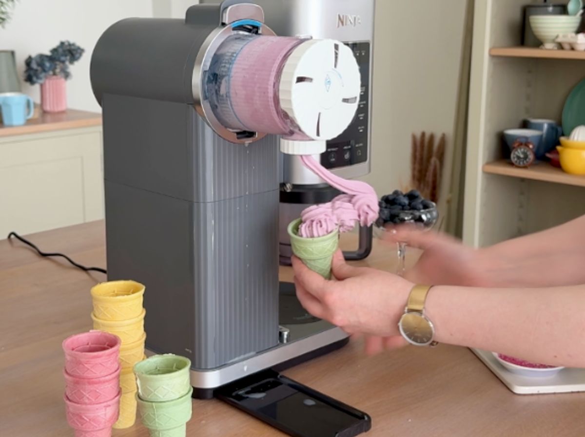 Eine Person hält ein Waffelhörnchen unter die Düse der Ninja Swirl, während zu viel Softeis hineingefüllt wird.