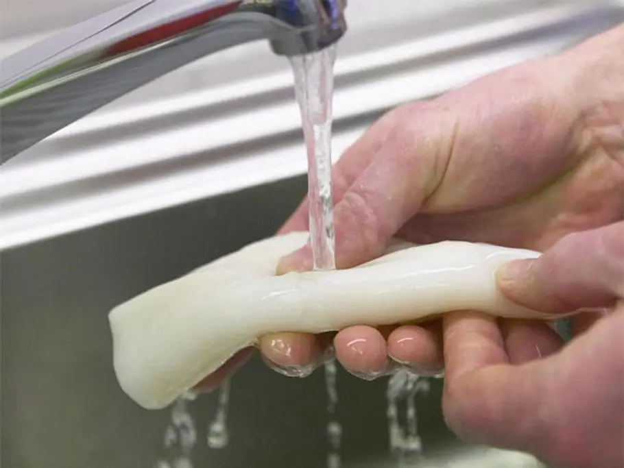 Eine Tintenfisch-Tube unter fließendem Wasser waschen.