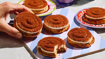Tiramisu-Cookies auf einem gestreiften Brettchen. Ein Cookie wird gerade genommen. - Foto: StockFood Studios/Meike Bergmann Tiramisu-Cookies auf einem gestreiften Brettchen. Ein Cookie wird gerade genommen. - Foto: StockFood Studios/Meike Bergmann