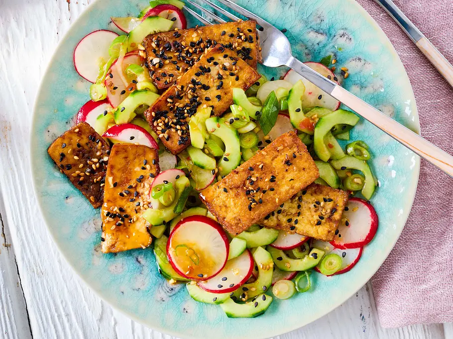 Tofu aus dem Airfryer mit Sesam bestreut und auf Gurken-Radieschen-Salat serviert.