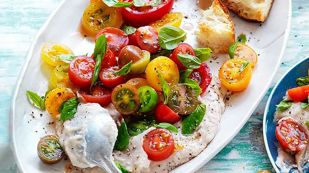 Bunter Tomatensalat auf weißer Bohnencreme, bestreut mit Basilikum, angerichtet auf einer ovalen weißen Platte - Foto: Are Media Syndication Bunter Tomatensalat auf weißer Bohnencreme, bestreut mit Basilikum, angerichtet auf einer ovalen weißen Platte - Foto: Are Media Syndication