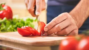 Mann schneidet Tomate mit einem Tomatenmesser - Foto: iStock/takoburito Mann schneidet Tomate mit einem Tomatenmesser - Foto: iStock/takoburito